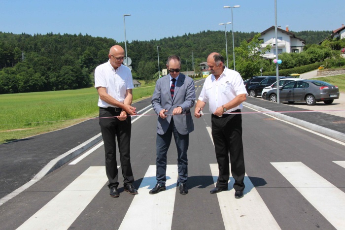 Prenovljeno cesto so s prerezom taku namenu predali (z leve): direktor Komunalnih gradenj Grosuplje Viktor Dolinek, državni sekretar na Ministrstvu za infrastrukturo Blaž Košorok, ki je zbrane tudi nagovoril, in župan Andrej Kastelic. 