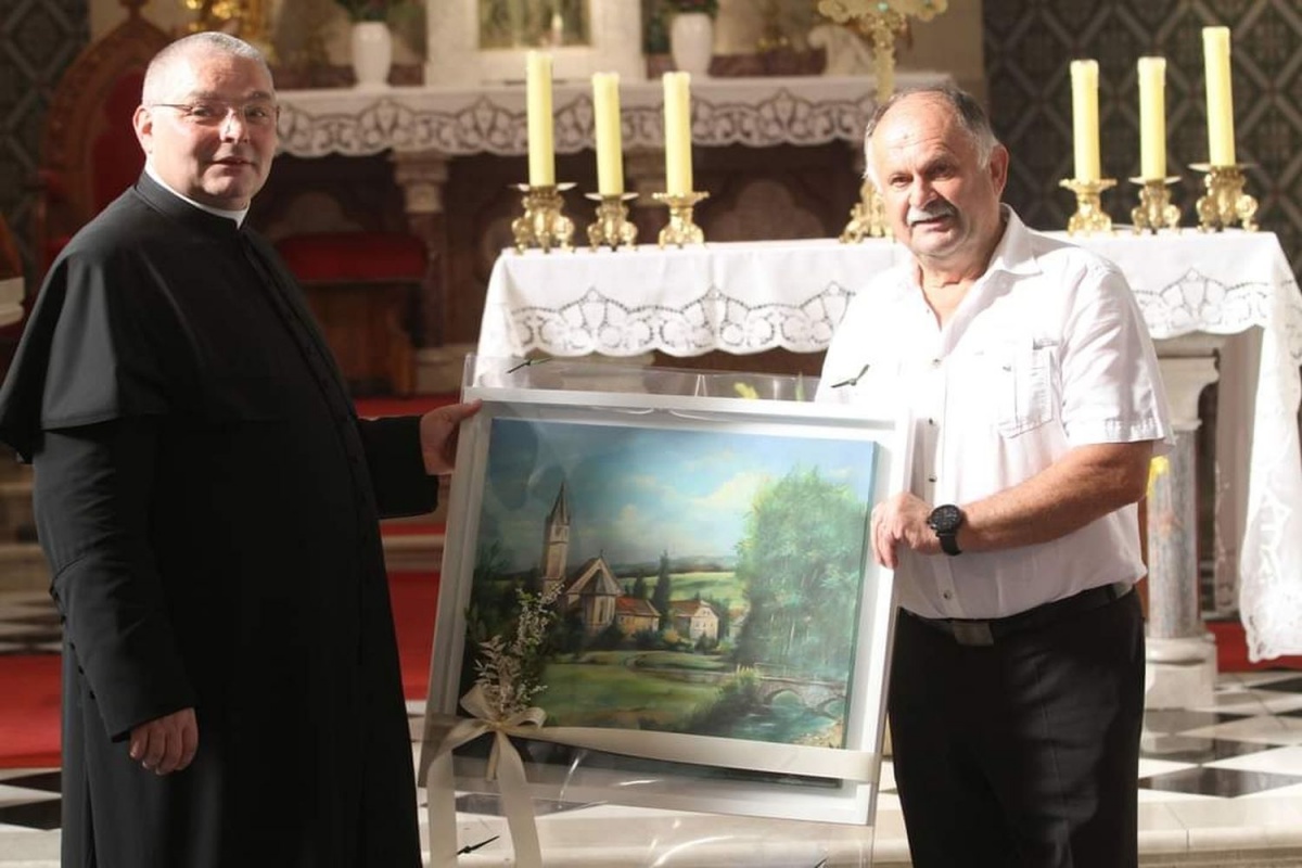 Mirnopeški župan Andrej Kastelic je dolgoletnemu župniku g. Janezu Rihtaršiču poklonil umetniško sliko mirnopeške doline s farno cerkvijo sv. Kancijana.