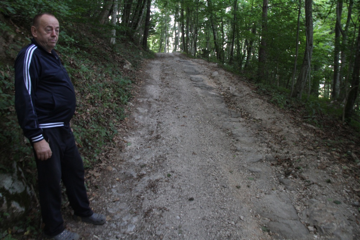 Anton Rozman ob cesti, ki pelje proti njegovi hiši. Približno 200 m dolg  makadamski odsek je v slabem stanju in potreben obnove. (Foto: R. N.)