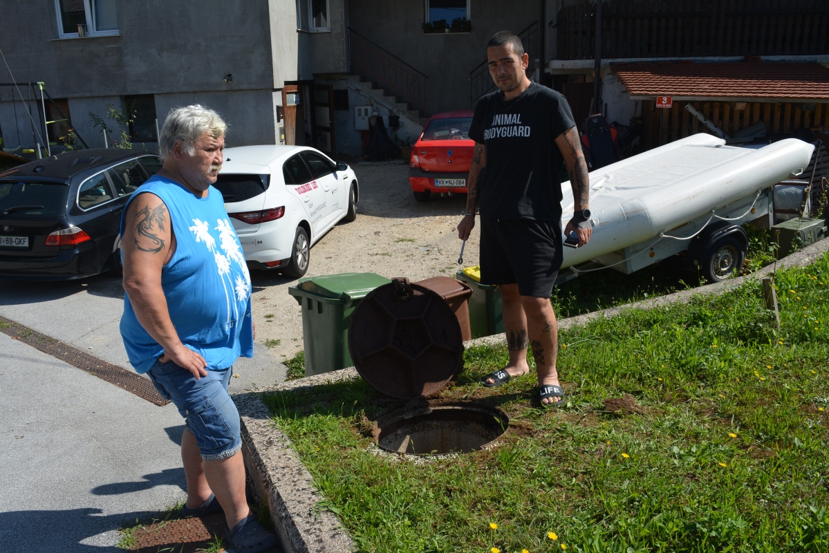 Rajko (levo) in Andraž Bedene ob jašku, kamor so očitno speljane meteorne in fekalne vode. (Foto: D. S.)