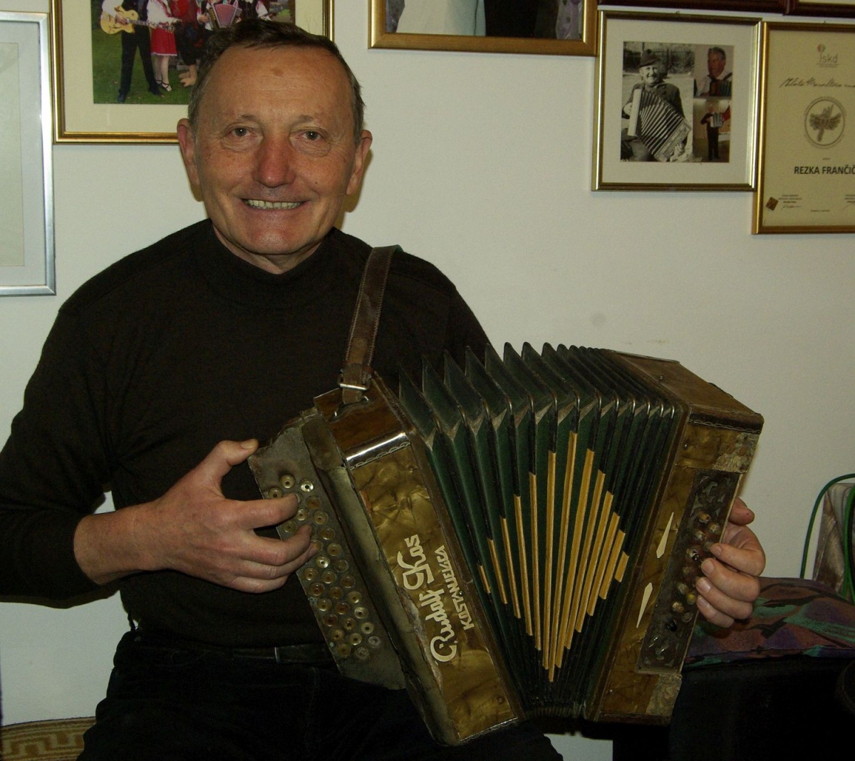 Slavko Frančič s skoraj osemdeset let staro harmoniko svojega očeta Lojzeta, ki je bil ljudski godec. (Foto: L. M.)